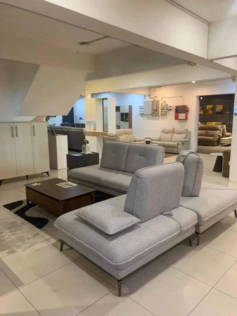 Modern living room with gray sectional sofa and coffee table in a showroom setting.